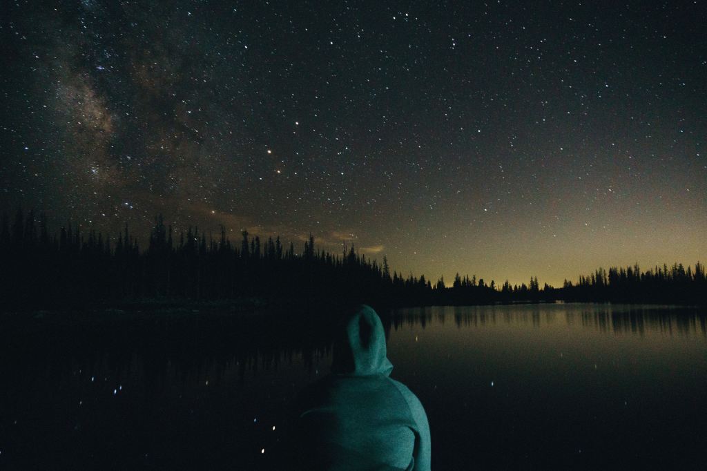 person in hoodie looking at a starry sky